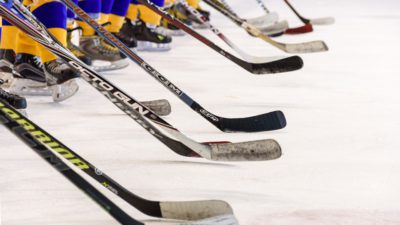 Hockeyspelare med blågula strumpor står på en linje med sina hockeyklubbor