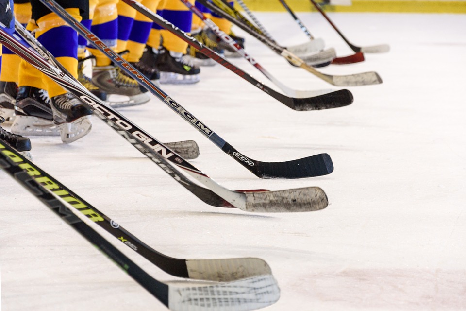 Hockeyspelare med blågula strumpor står på en linje med sina hockeyklubbor