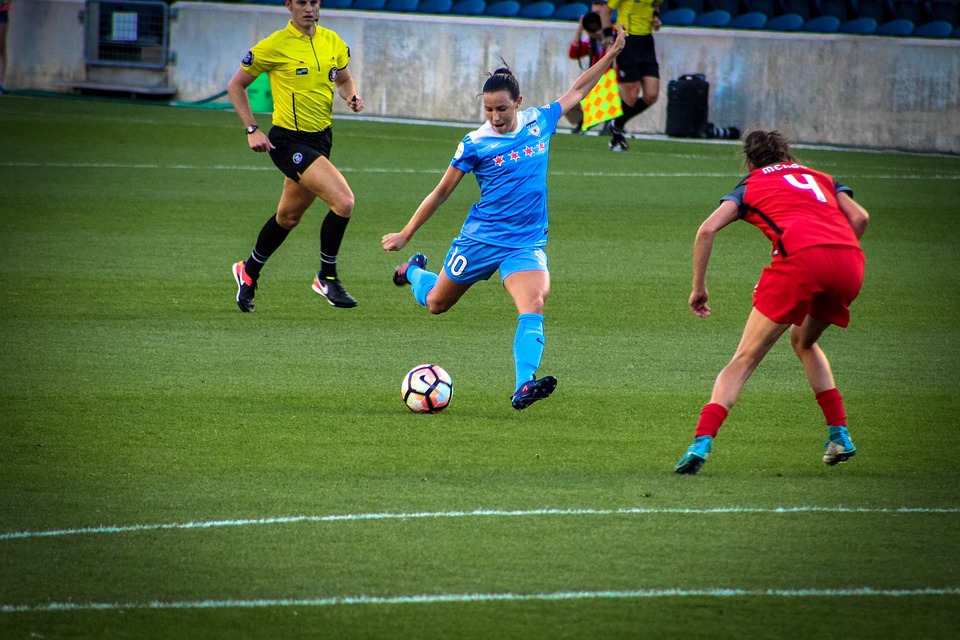 En fotbollsspelare i blåa kläder sparkar på en fotboll