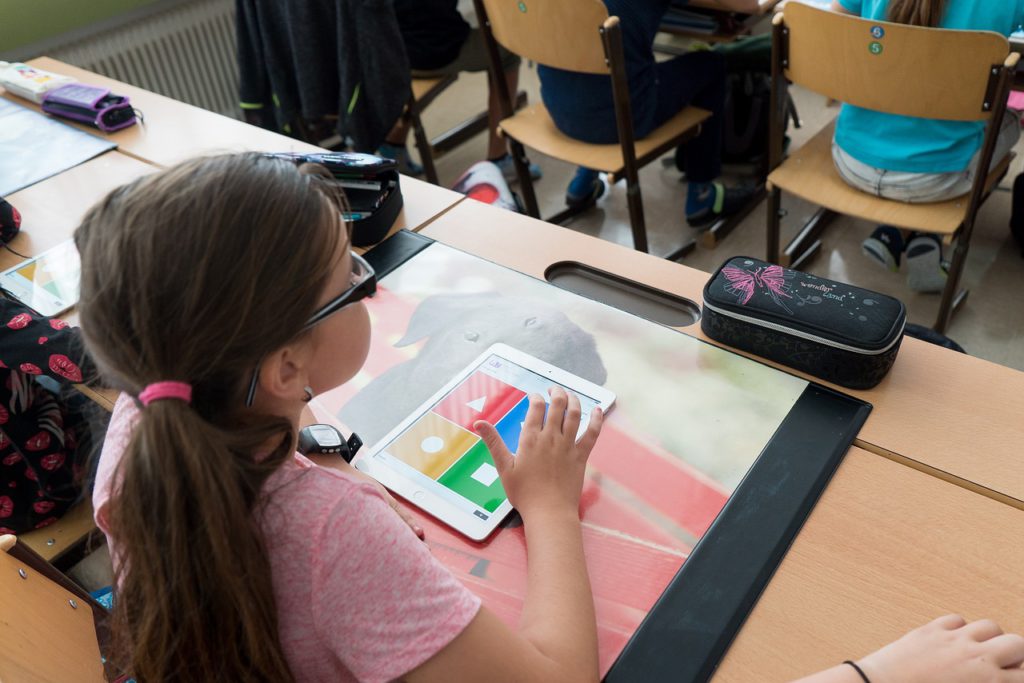 En elev sitter vid sin skolbänk med en läsplatta