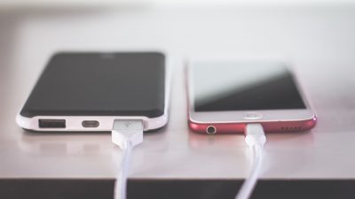 Två telefoner blir laddade med olika slags laddsladdar.